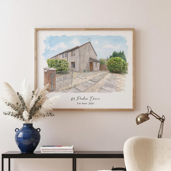 May include: A framed watercolour painting of a house with a stone facade, a pathway, and a small garden. The artwork is framed in a light wood frame. The text "63 Parker Drive Est. June 2020" is printed at the bottom.